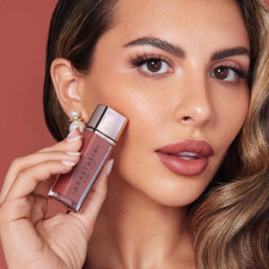 Woman holding a lip gloss with a close-up of her face