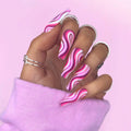 Hand with pink and white wavy nail art on a pink background