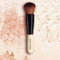 Bobbi Brown makeup brush on a textured beige background