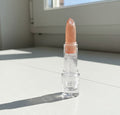 Clear lip balm with a pink top on a light surface