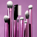 Set of pink makeup brushes with black handles on a purple background