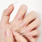 Clear nail extensions held between fingers against a light background