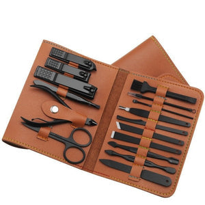 Manicure set with black tools in a brown leather case on a white background