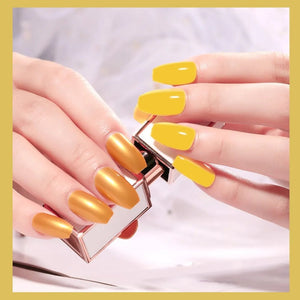 Close-up of hands with yellow nail polish holding a small object.