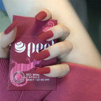 Hand holding a pink box labeled 'Red Wine' with red nail polish.