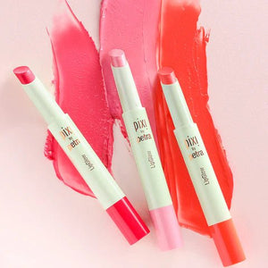 Three lip glosses with pink and red shades on a pink background
