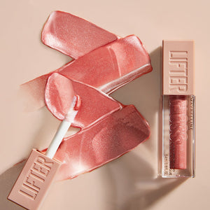 Pink lip gloss with applicator and packaging on a beige background