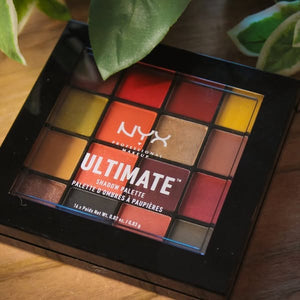 NYX Ultimate Shadow Palette on a wooden surface with green leaves in the background