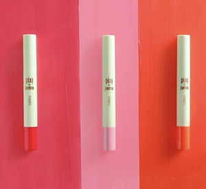 Three 'pixi' beauty products on a pink and red striped background