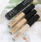 Three NARS concealer bottles with their packaging on a floral background
