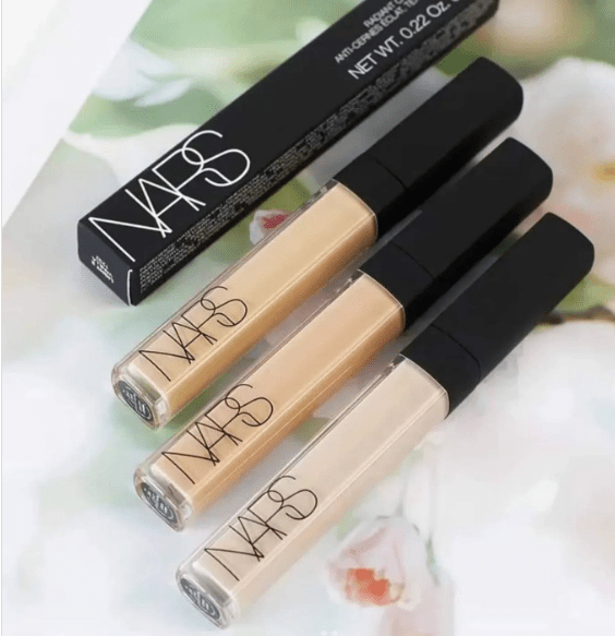 Three NARS concealer bottles with their packaging on a floral background