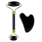 Black and gold facial roller with a heart-shaped black tool on a white background