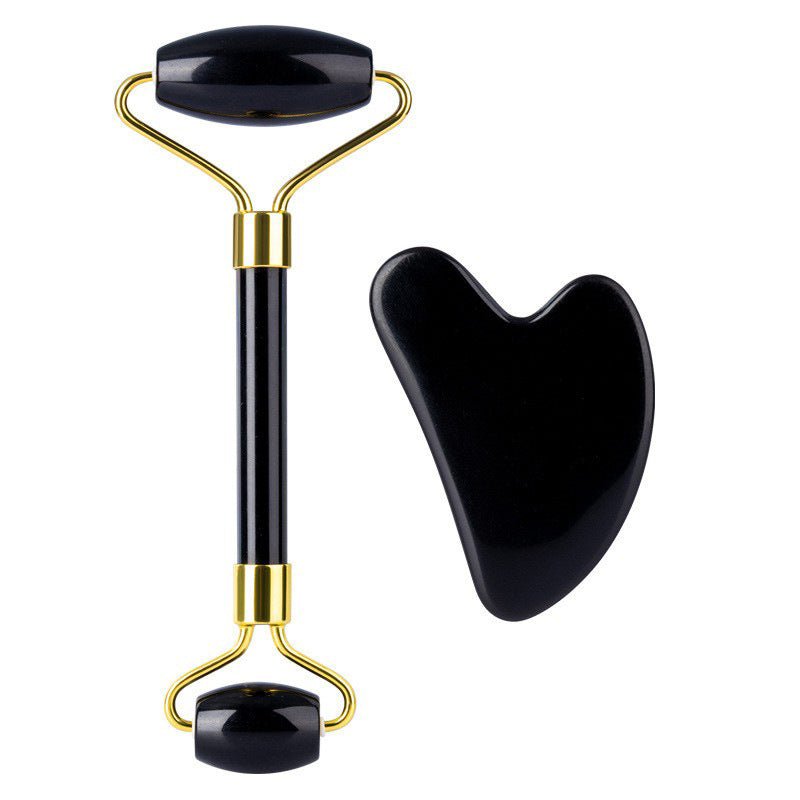 Black and gold facial roller with a heart-shaped black tool on a white background