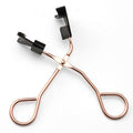 Rose gold eyelash curler on a white background