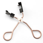 Rose gold eyelash curler on a white background