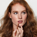 Woman applying lipstick with a neutral background