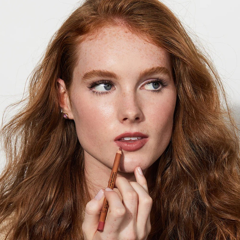 Woman applying lipstick with a neutral background