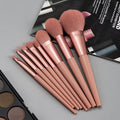 Set of makeup brushes with rose gold handles on a gray surface.
