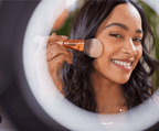 Woman applying makeup with a brush in front of a circular mirror