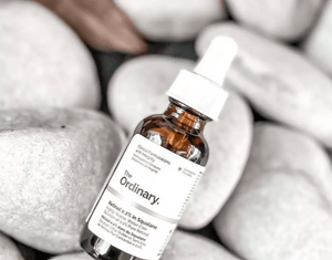 Bottle of 'The Ordinary' serum on a background of textured stones
