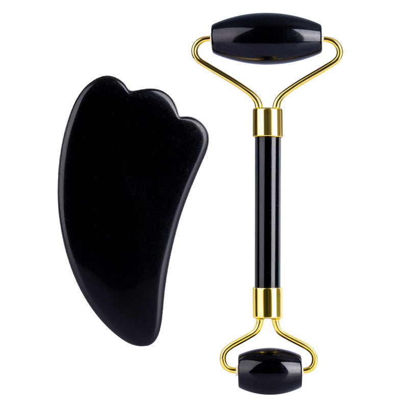 Black facial roller and gua sha tool on a white background