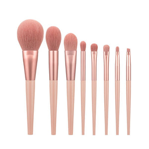 Set of rose gold makeup brushes on a white background