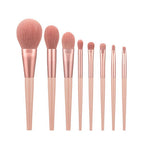 Set of rose gold makeup brushes on a white background