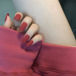 Close-up of a hand with red nail polish wearing a pink sleeveless top.