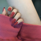 Close-up of a hand with red nail polish wearing a pink sleeveless top.